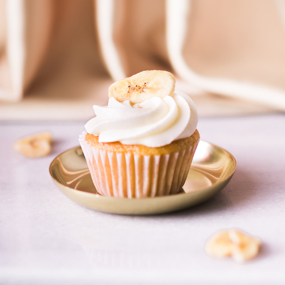 Indulge in a scrumptious banana cupcake, topped with creamy frosting and a caramelized banana slice. Pair it perfectly with a crisp and refreshing Brut Rose Cava, with its bright fruit notes that complement the cupcake&